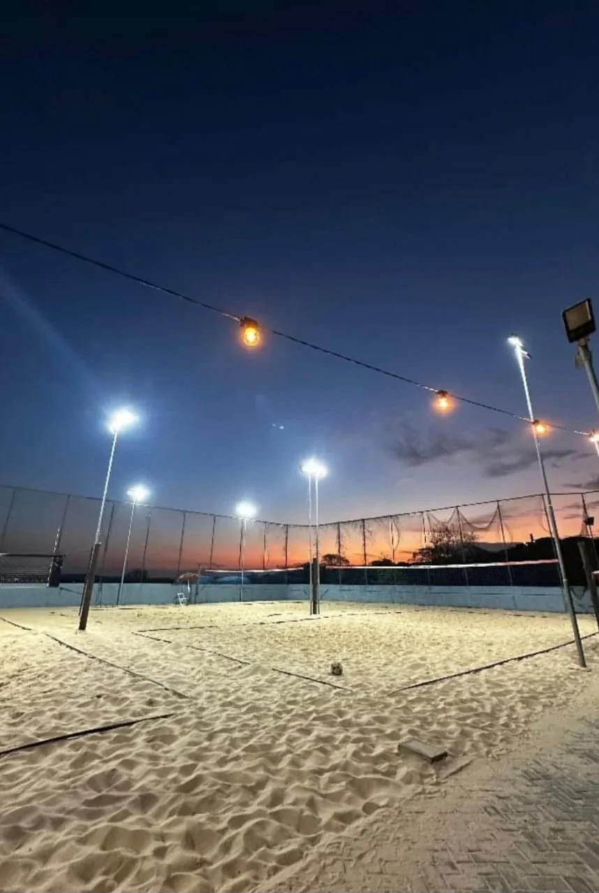 Quadras de areia da Arena CHT iluminadas à noite, com refletores e varal de luzes